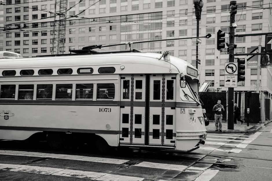 Monochrome image of a classic tram in an urban setting, emphasizing public transport and city life.