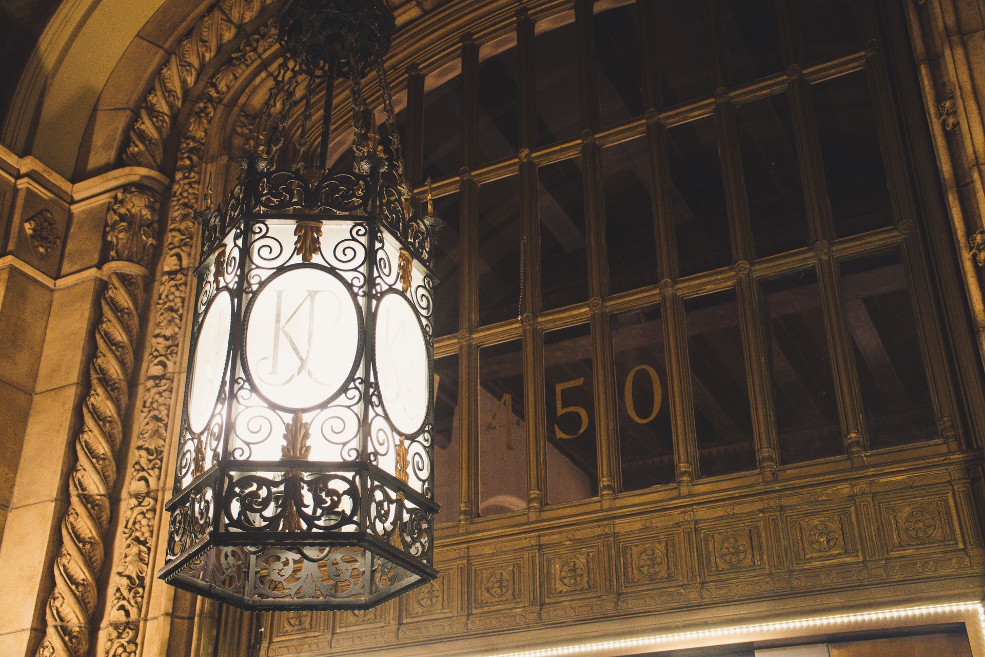 A vintage chandelier hanging in an ornate interior setting, showcasing intricate architectural details.