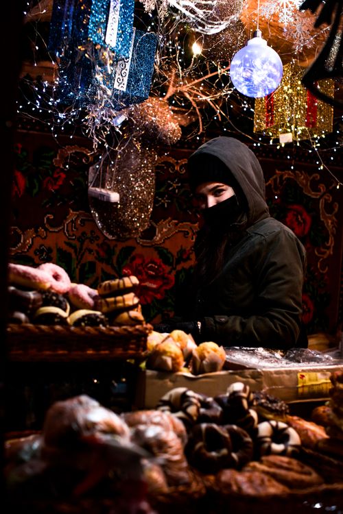 Free A festive market scene with a variety of pastries and a warmly dressed woman. Stock Photo
