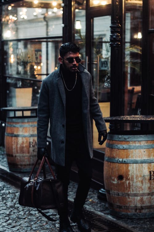 Man in a Gray Coat Carrying a Duffle Bag