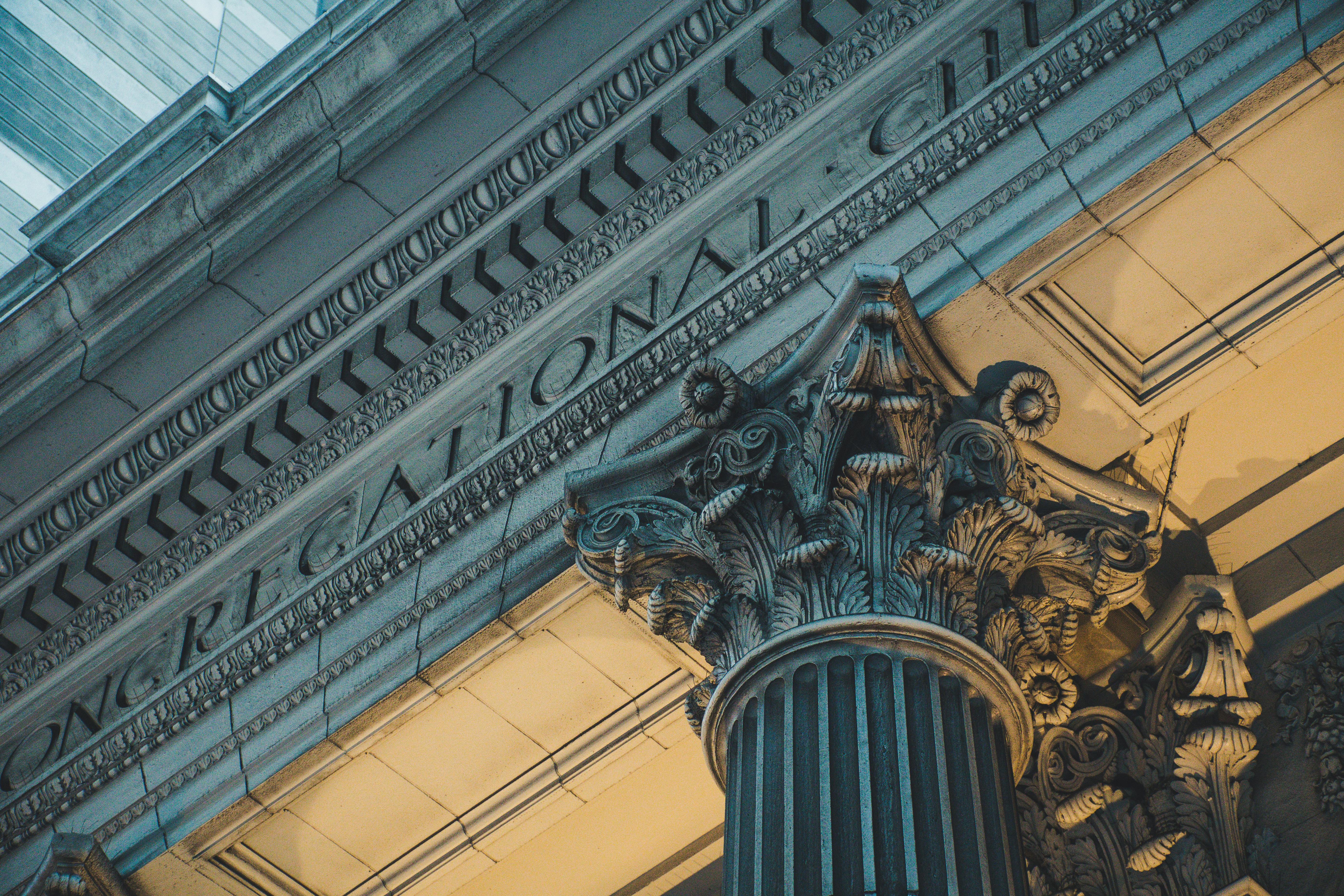 Close-up of a detailed architectural column with ornate designs in an urban setting.