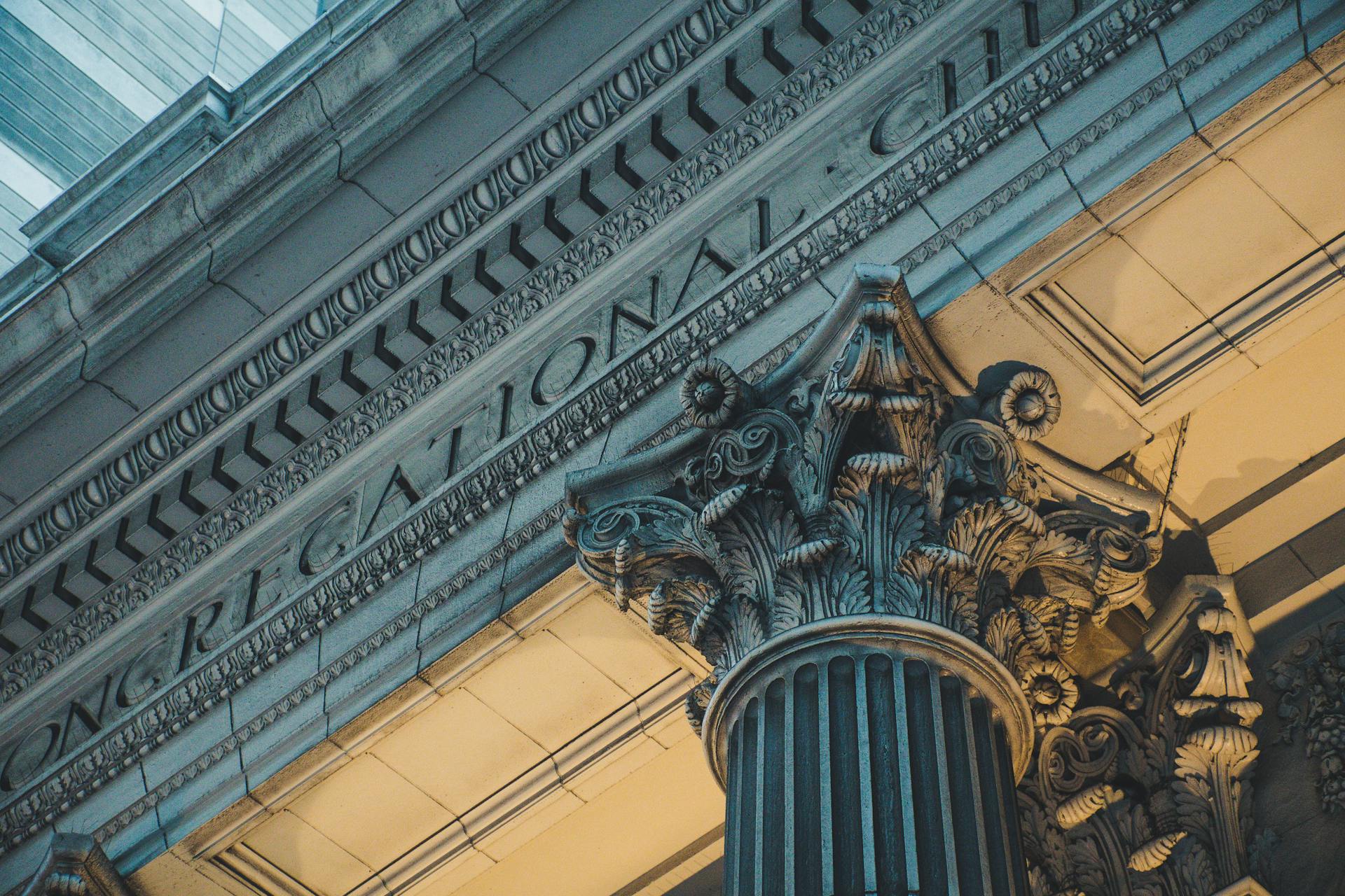 Close-up of a detailed architectural column with ornate designs in an urban setting.