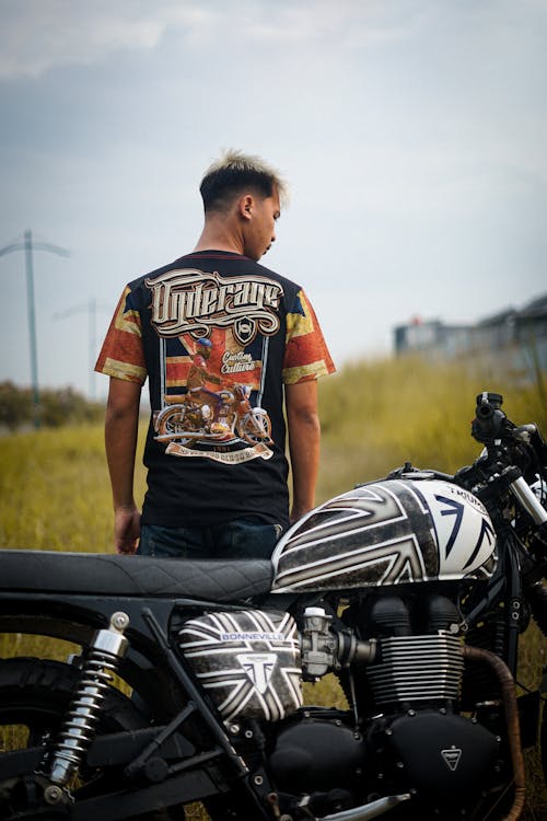 Man in Black and Red Crew Neck T-shirt Standing Near on Black Motorcycle