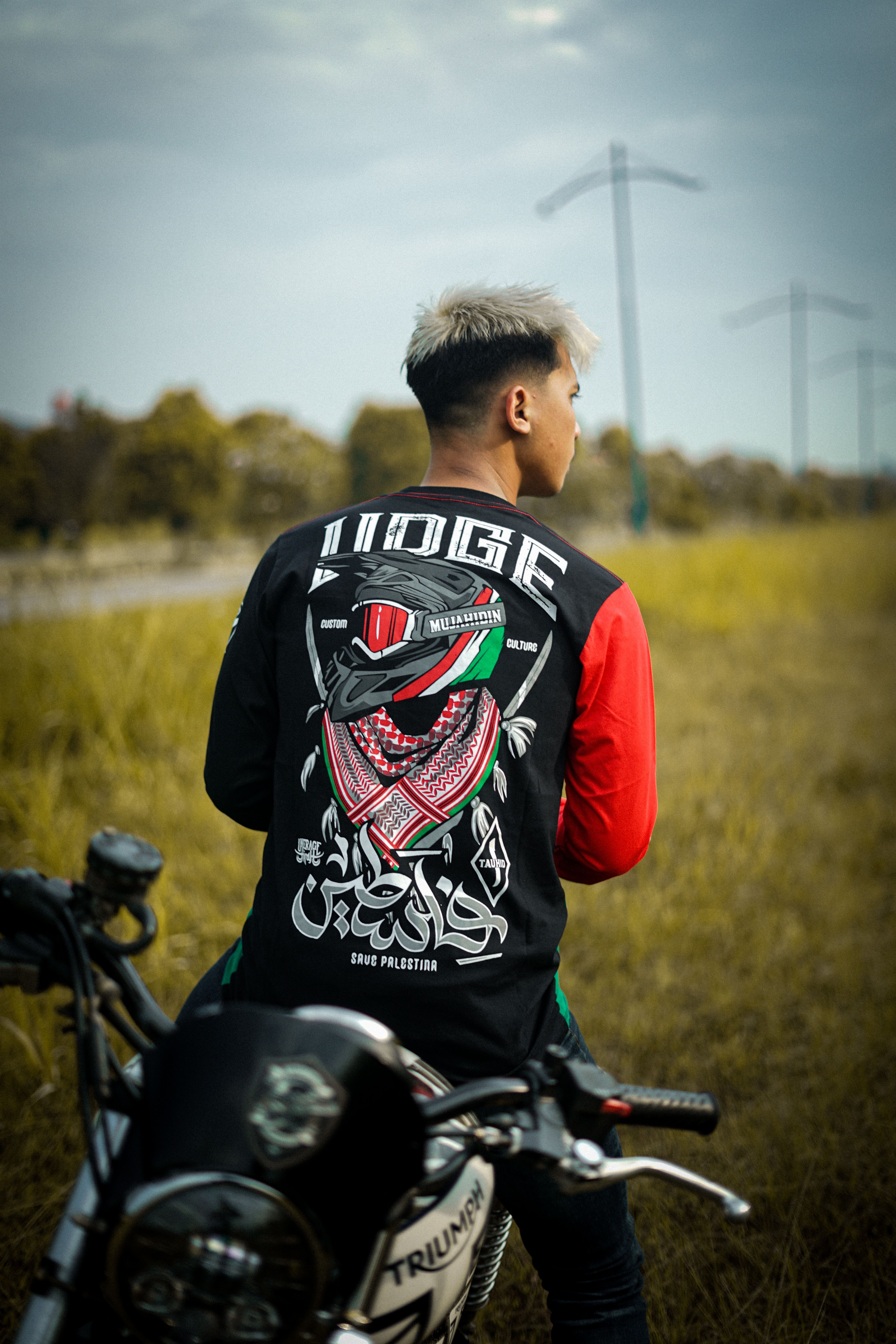 Young biker sitting on a motorcycle wearing a distinctive printed shirt outdoors.
