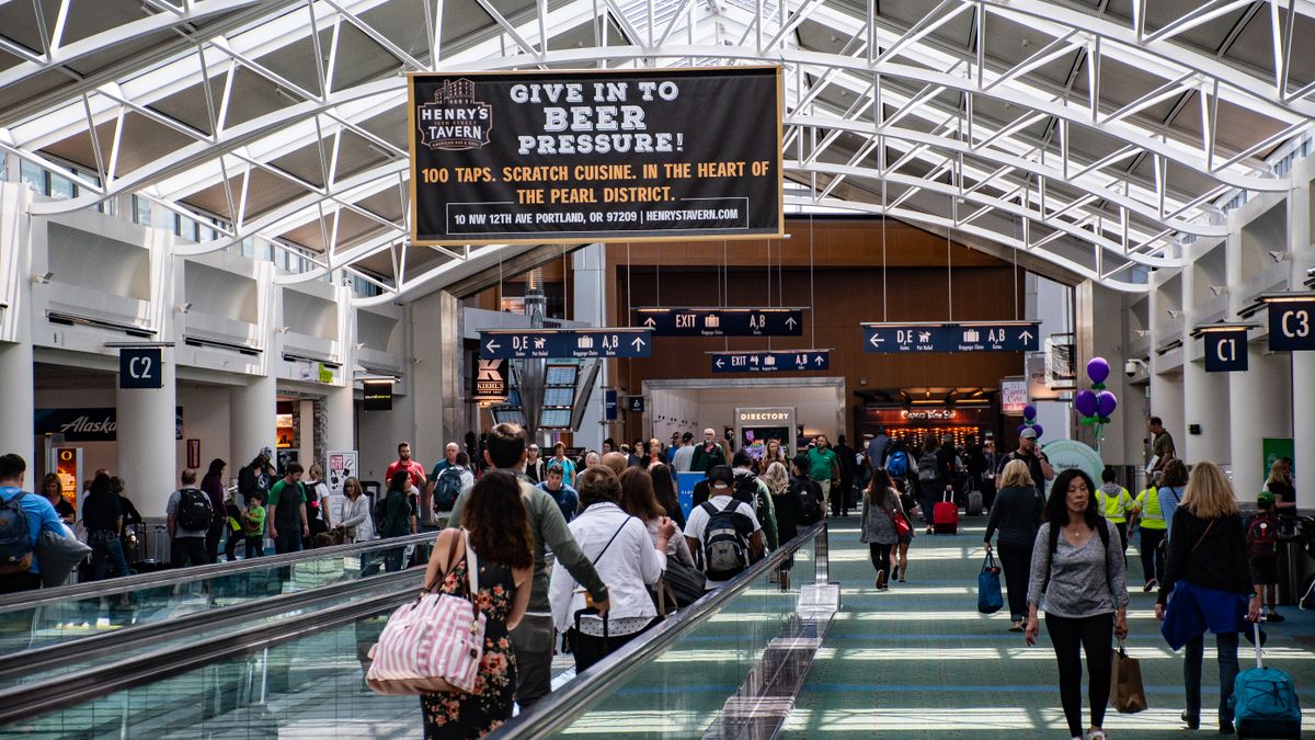 Crowds of people walking through a modern airport terminal, vibrant travel atmosphere.