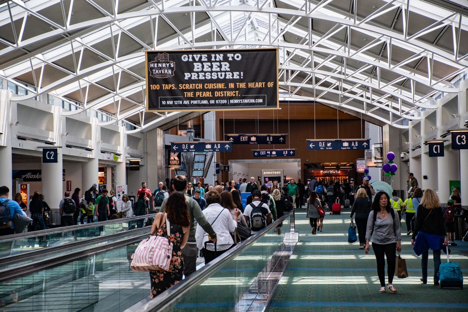 Crowds of people walking through a modern airport terminal, vibrant travel atmosphere.