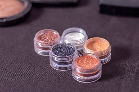 Variety of glitter eyeshadows in small containers on a dark background.