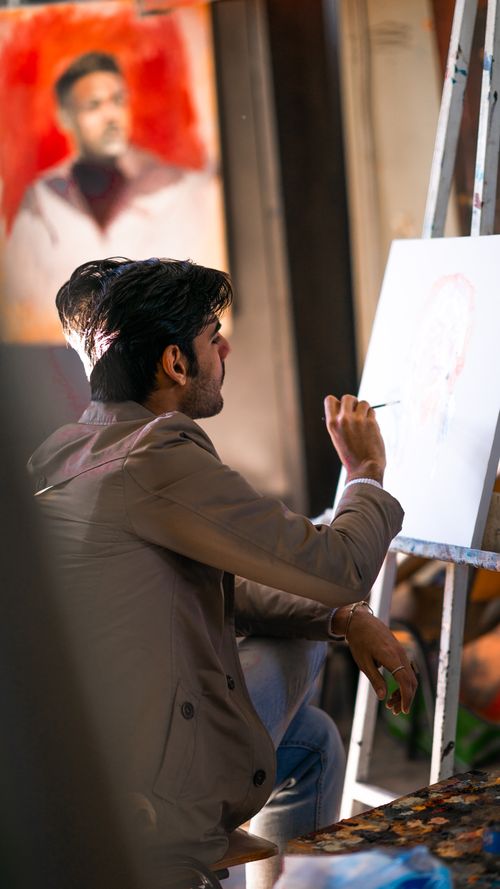 Free A focused artist paints a portrait in a bright studio, capturing creativity in progress. Stock Photo
