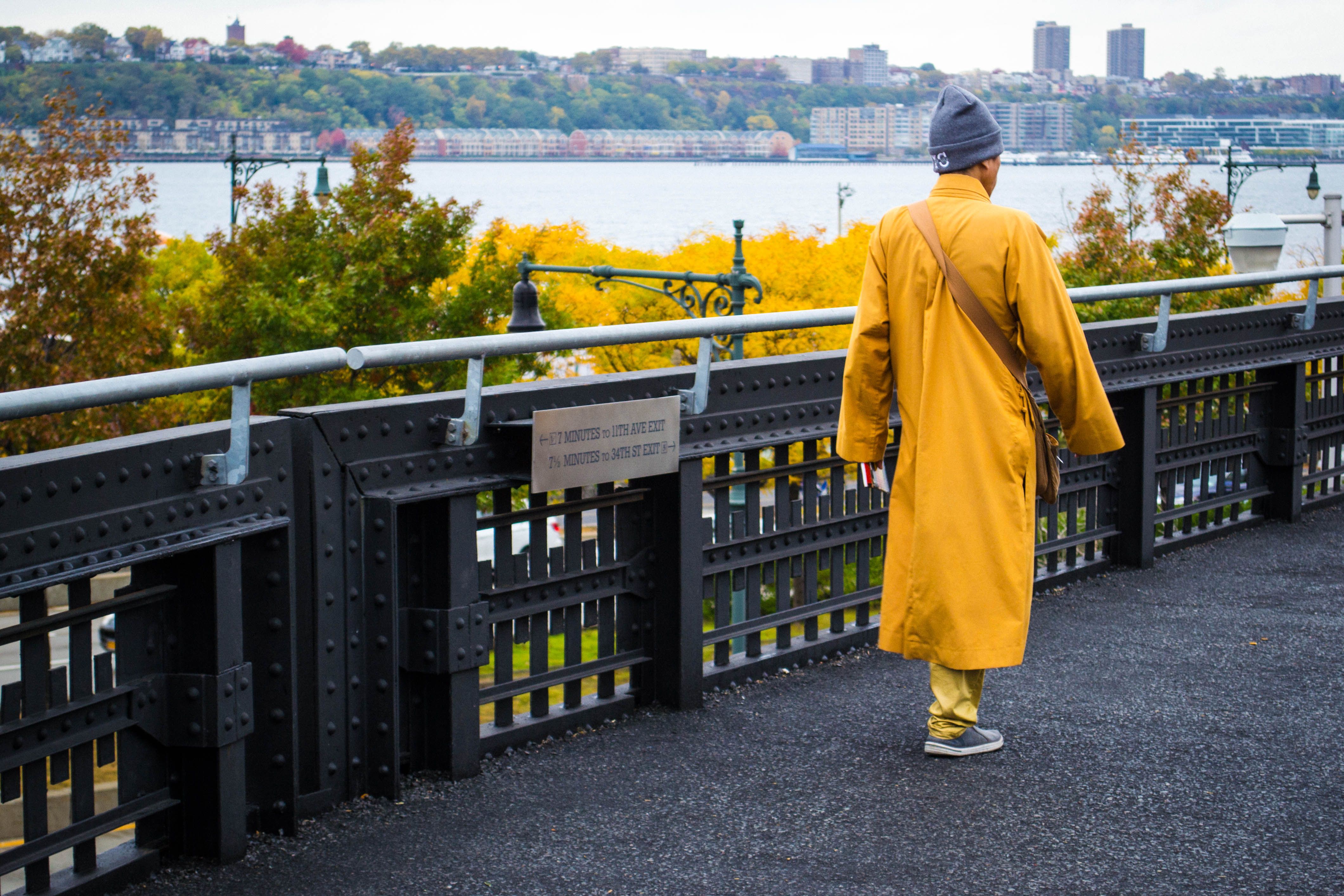 A Person in Yellow Coat Walking Near the Metal Railing · Free Stock Photo
