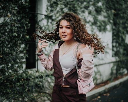 Stylish woman with long curly hair walking outdoors, exuding confidence and elegance.