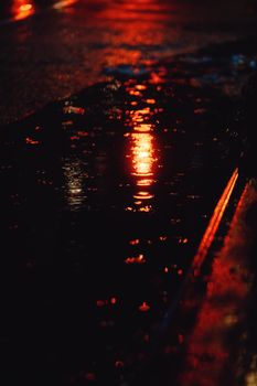 Warm streetlights reflecting in water on a wet road at night.