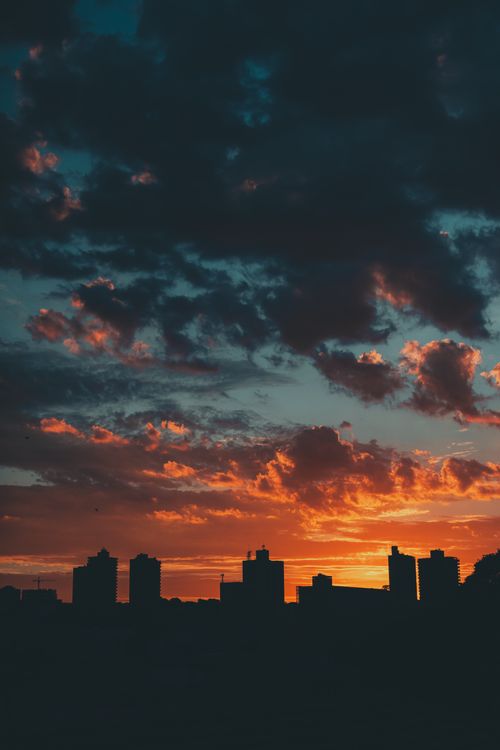 Free A dramatic cityscape silhouette against a vibrant sunset sky. Stock Photo