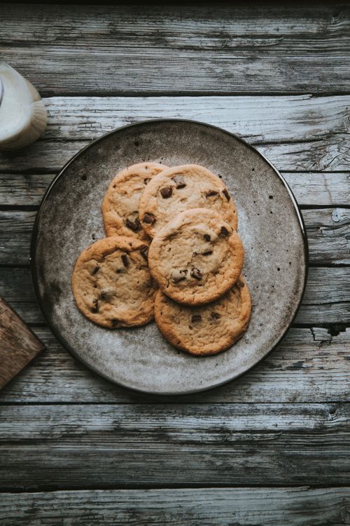 Free Delicious chocolate chip cookies on a rustic wooden table, perfect for dessert lovers. Stock Photo