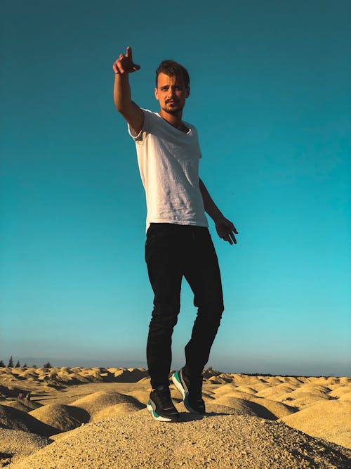 Man in White Shirt Standing on Brown Sand