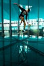 Woman in Black Tank Top and Blue Shorts Jumping on Pool