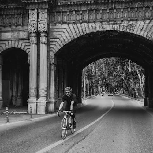 Grayscale Photo of a Man Riding a Road Bike
