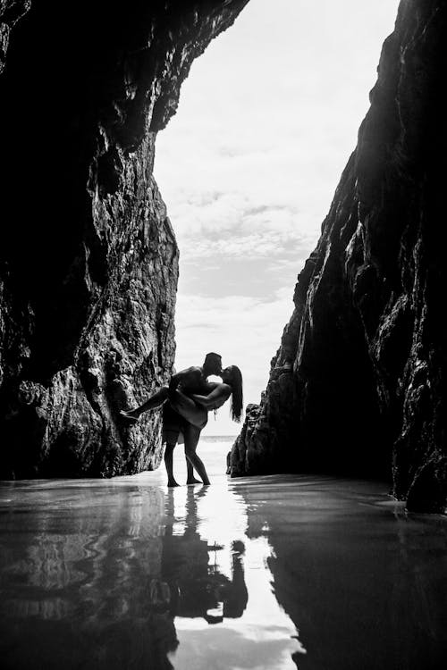 Grayscale Photo of a Couple Kissing in a Cave
