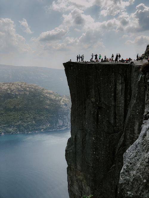 Free Tourists admire the stunning view from the famous Preikestolen cliff in Norway. Stock Photo