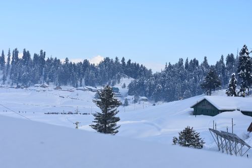 Free Spectacular snowy landscape with mountains, trees, and houses under a clear sky in winter. Stock Photo