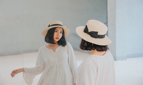 Wanita Mengenakan Gaun Lengan Panjang Putih Dan Topi Matahari Beige
