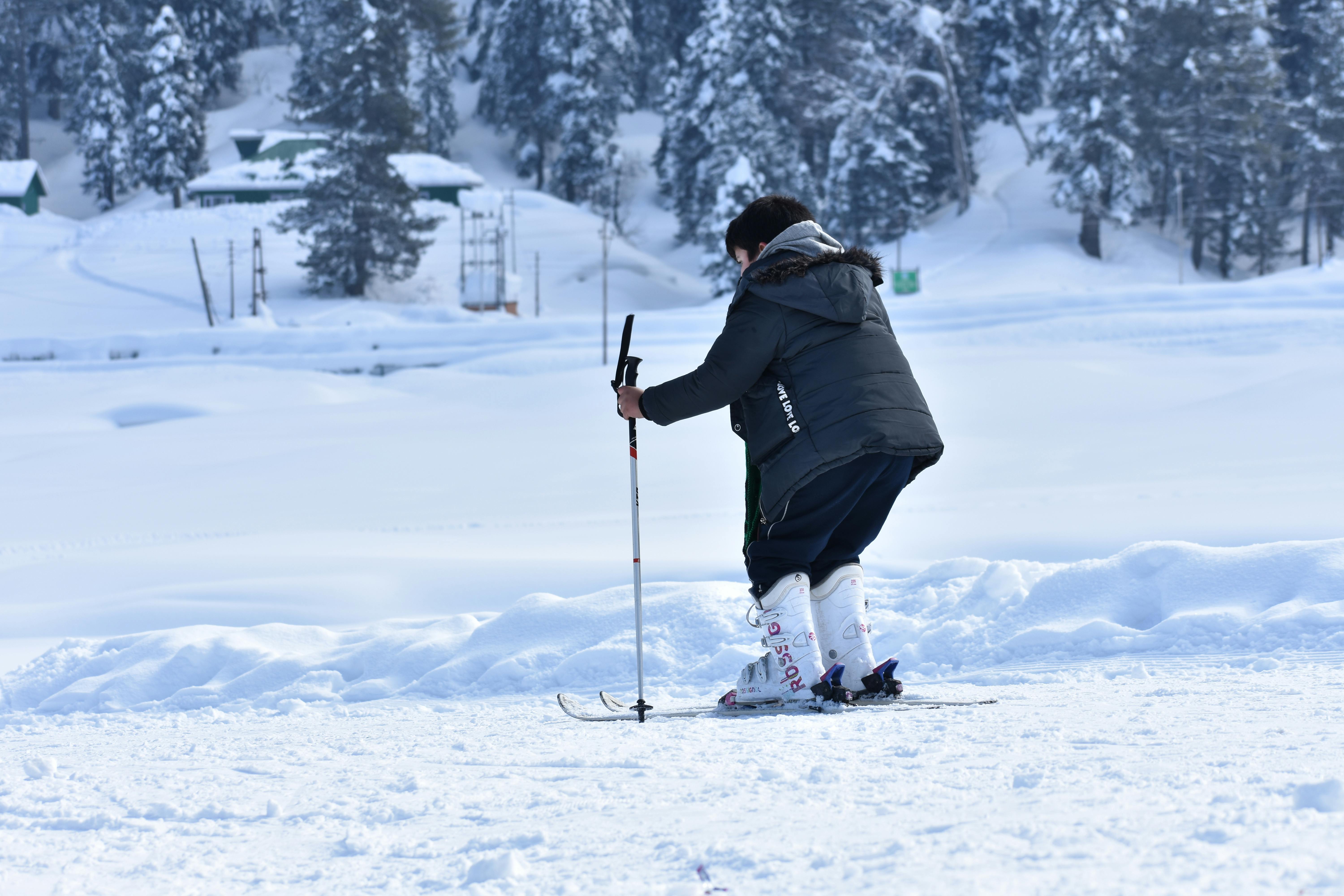 Prescription Goggle Inserts - Skier navigating snowy terrain at a winter resort surrounded by snow-covered trees.