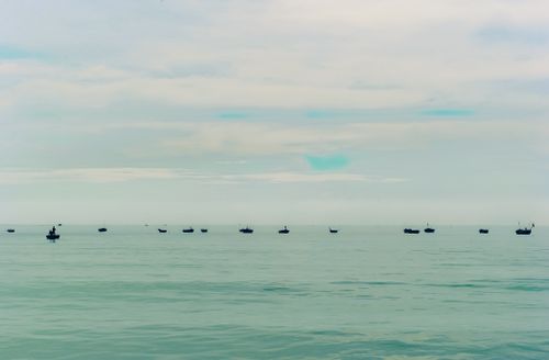 Free A serene ocean view with scattered small boats under a cloudy sky. Stock Photo