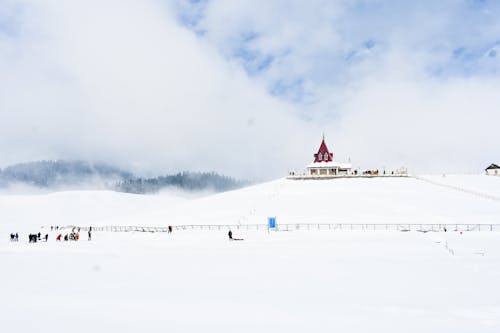 People on Snow near Hill with Building