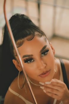 Stunning portrait of a woman with striking makeup and accessories captured indoors.