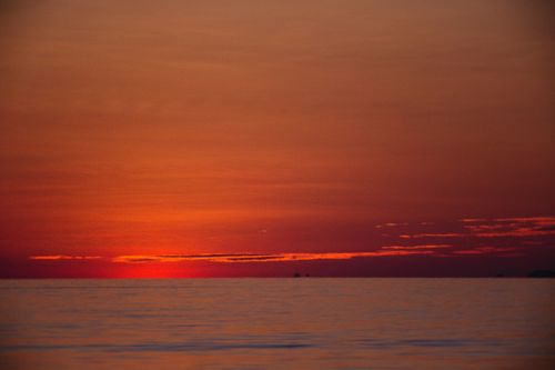 Free Breathtaking view of a fiery sunset casting a warm glow over calm ocean waters. Stock Photo