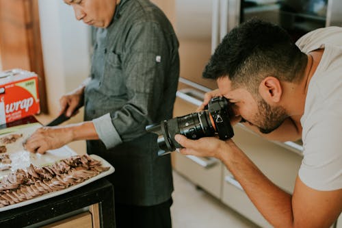 A Man in White Shirt Taking Photos of the Food on the Tray