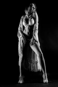 Elegant black and white photo of a woman in lingerie striking a sensual pose in the studio.