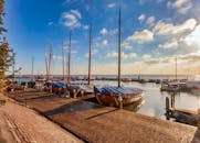 宁静的港口，木船停泊在日出时分晴朗的天空下，水面上倒映着这一切