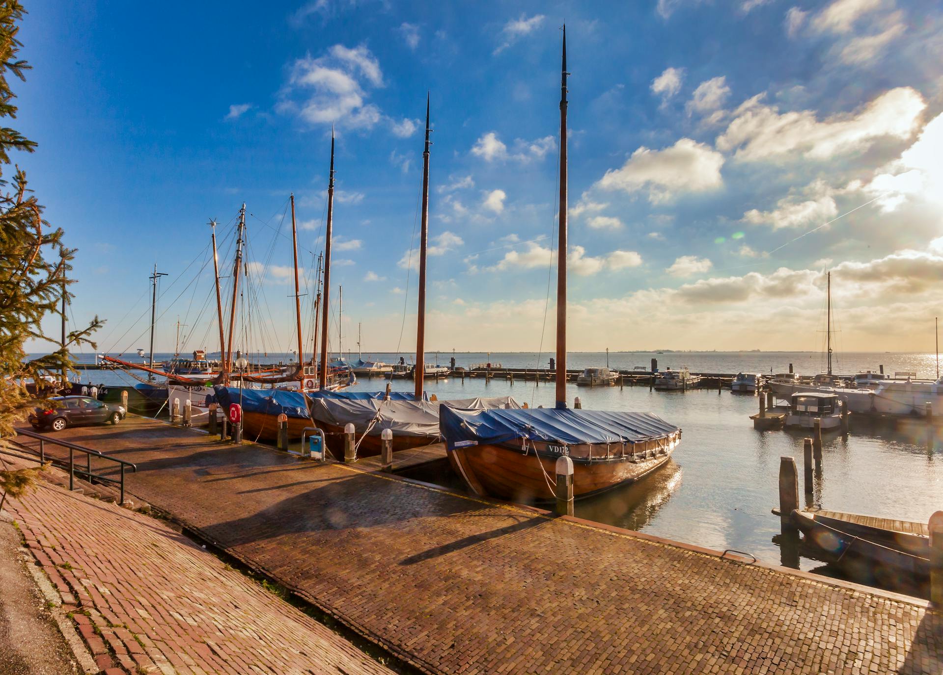 Serene harbor scene capturing wooden boats moored at sunrise with clear skies and reflections.