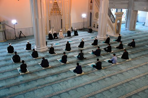Free Men gathered inside a mosque in Moscow, engaged in prayer, showcasing Islamic spirituality and community. Stock Photo