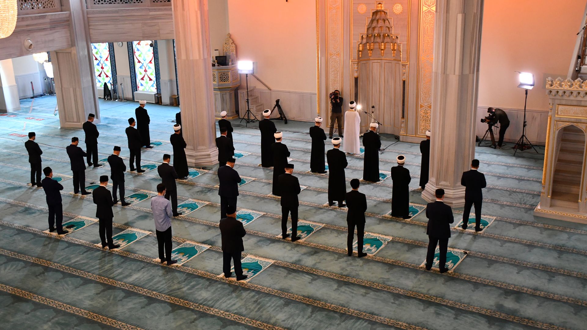 A group of Muslims gathered for prayer inside a Moscow mosque, captured from above.