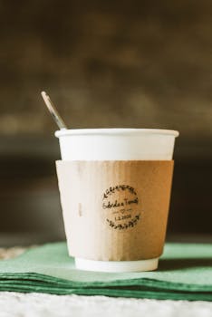Close-up view of a hot drink in a paper cup with sleeve, perfect for cozy moments.