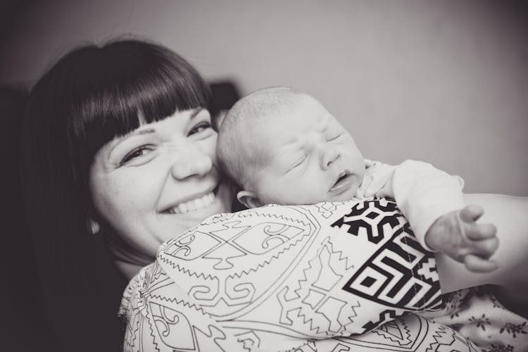 A Happy Woman Carrying Her Sleeping Baby