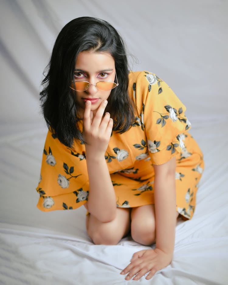 Young Brunette Woman In Orange Dress Kneeling On White Sheets