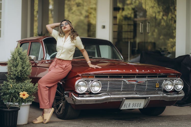 Blond Woman Leaning Against Red Vintage Car