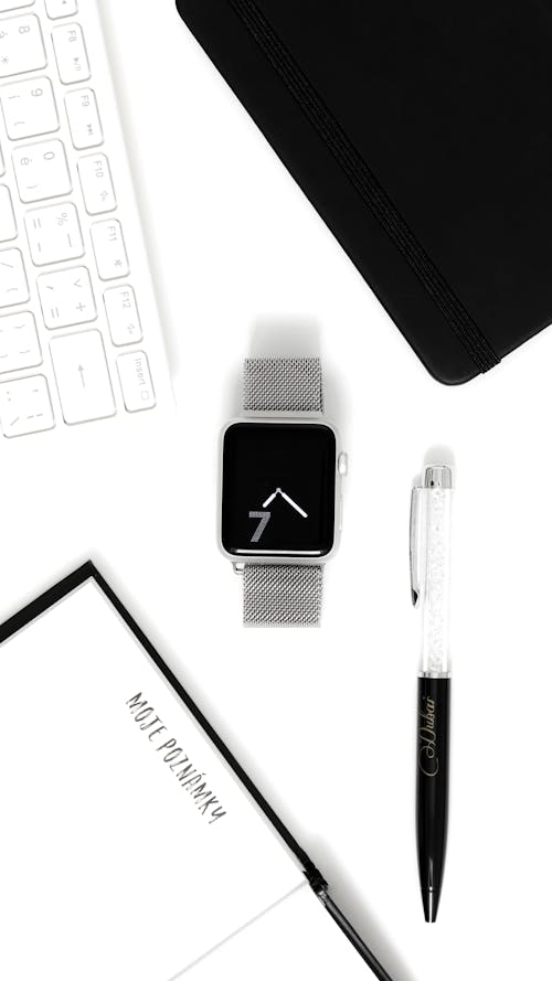 Smartwatch and a Pen on White Surface