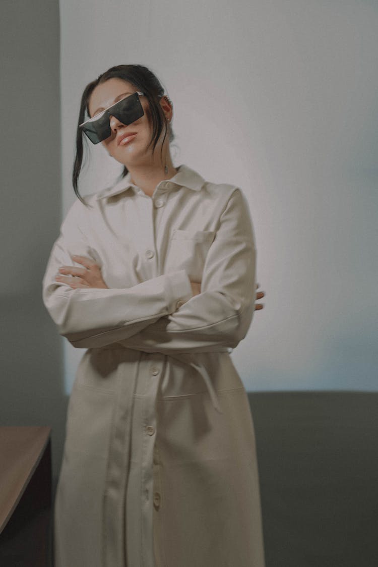 A Woman In Button Down Dress And Sunglasses Posing With Her Arms Crossed