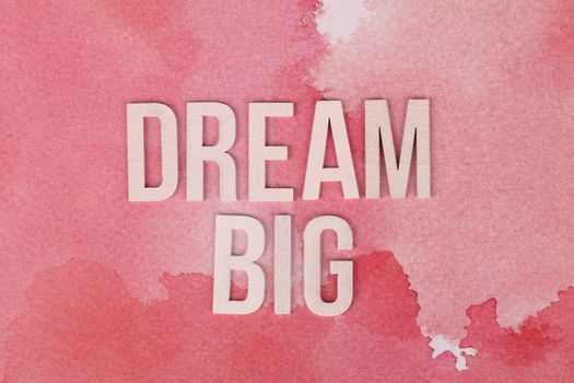 Motivational 'Dream Big' text on a pink watercolor background for encouragement.