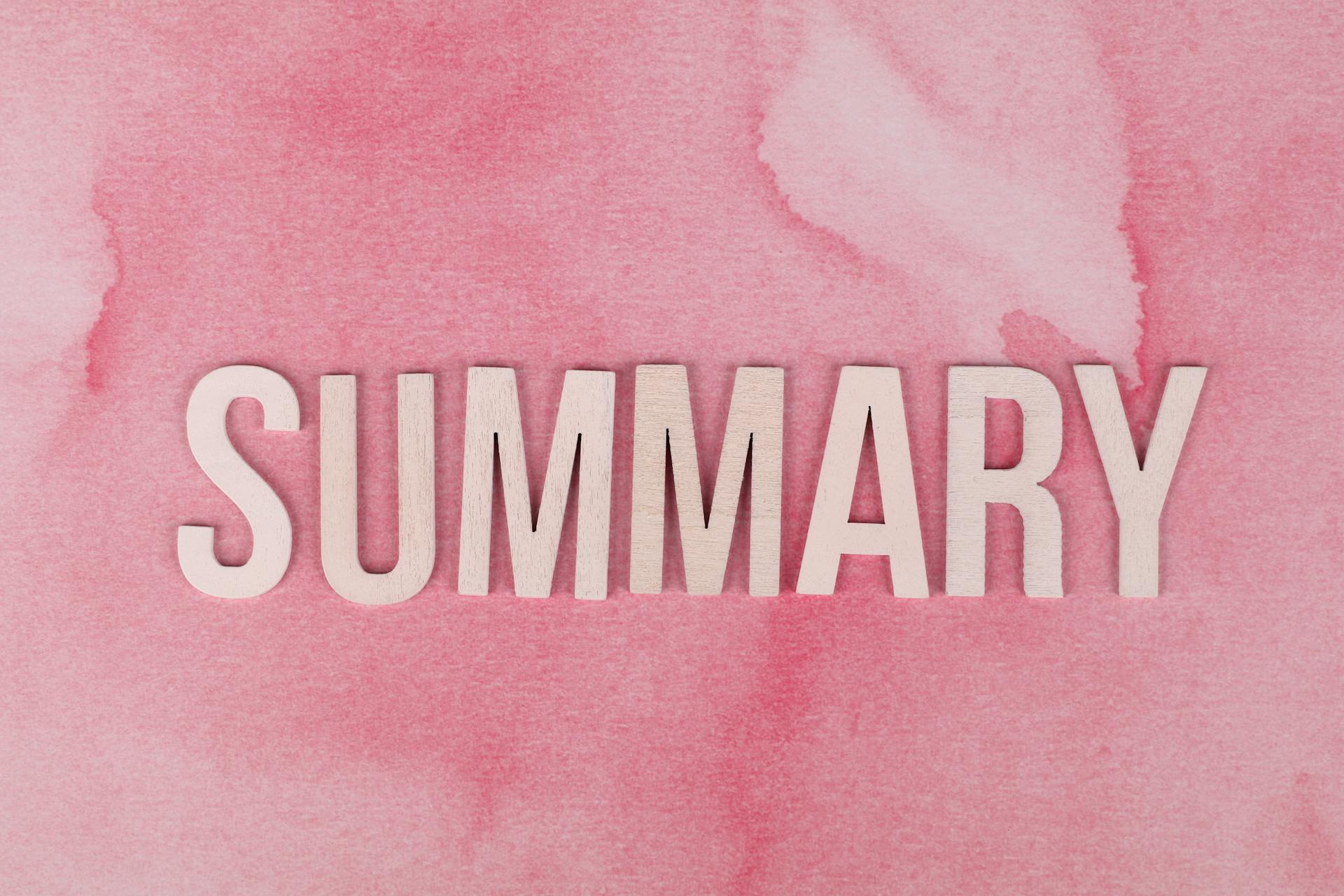 Wooden letters forming 'SUMMARY' on a pink watercolor background.