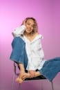 Woman with Curly Blond Hair Sitting in Chair and Smiling