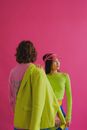 Women In Colorful Clothes Standing on Pink Background
