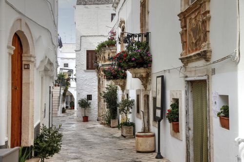 Free Picturesque alley with white buildings and flowers in Locorotondo, Italy. Stock Photo