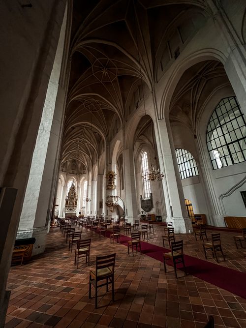 Free High-vaulted Gothic cathedral interior showcasing architectural elegance and wooden chairs. Stock Photo