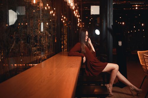 Free A woman in a maroon dress sitting in a cafe with ambient lighting. Stylish and serene setting. Stock Photo