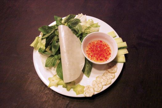 A vibrant Vietnamese appetizer platter with fresh vegetables and dipping sauce.