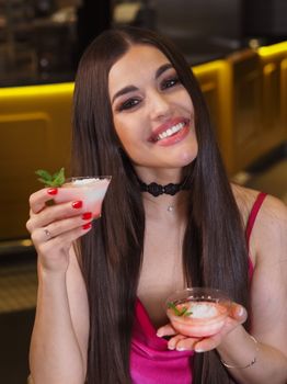 Woman holding two cocktails garnished with mint and smiling, perfect for lifestyle and food themes.